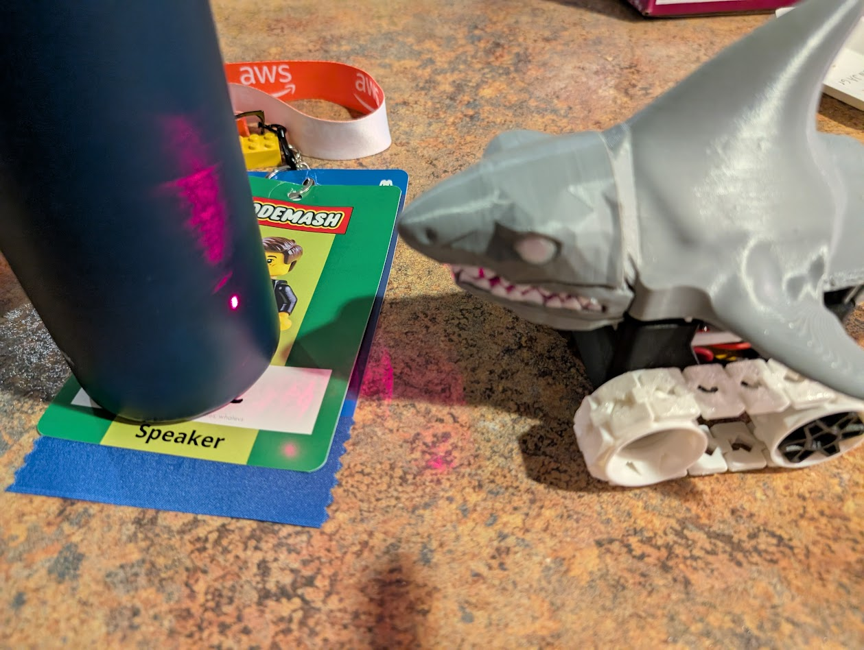 3D printed shark robot with a laser, aimed at a water bottle